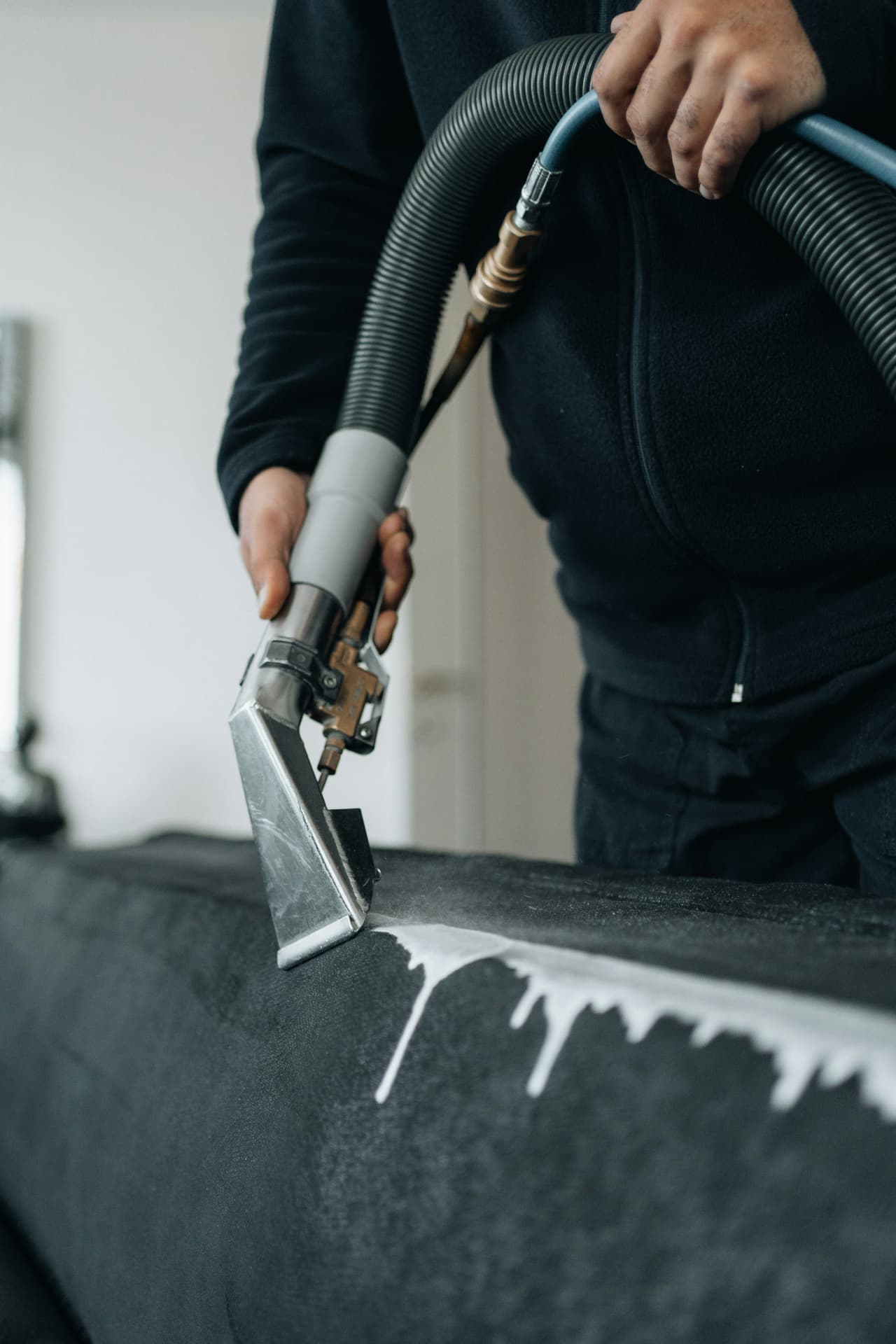 Upholstery cleaner extracting foam from a dark sofa