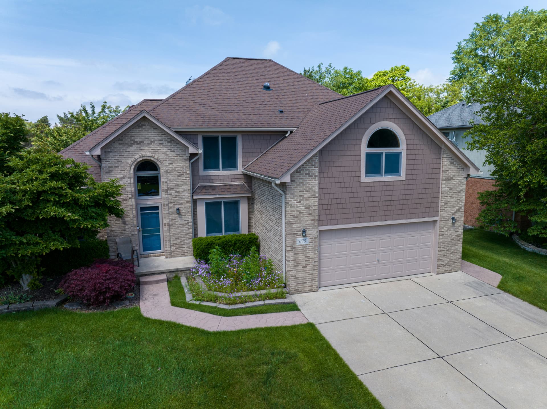 A clean two-story brick home with green lawn and landscaping